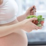 healthy nutrition and pregnancy. pregnant woman’s belly and vegetable salad
