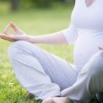 Young pregnant model meditating outside. Close-up