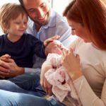 Family Sitting On Sofa With Newborn Baby