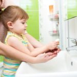 child girl washing hands with soap in bathroom